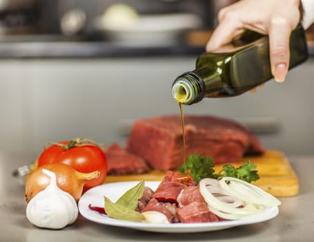 Chef pours olive oil on meat fillet