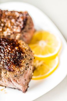 appetizing medallion on a plate with lemon wedges