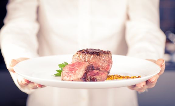 Chef keeps a dish of medallions in hands