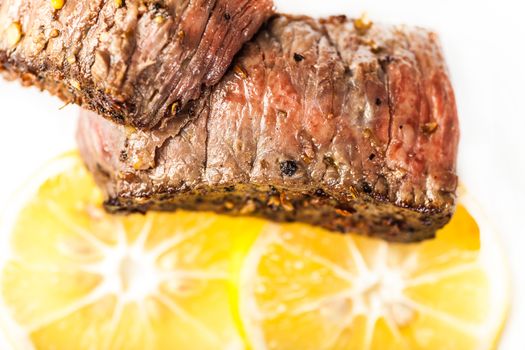 Sliced fried meat with slices of lemon closeup on a light background