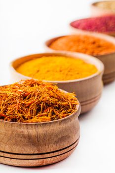 saffron,paprika,sumac,turmeric in a wooden bowl on white background