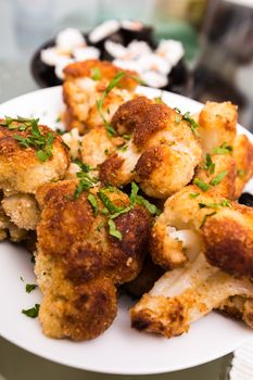 breaded and fried a cauliflower lying on a plate with parsley