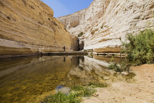 Tourists pass a water source in a deep gorge