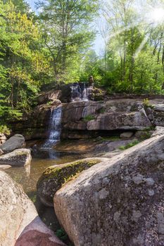 landscape rock with a waterfall and green forest