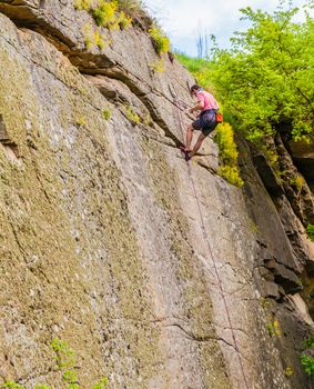 male athlete mountain climber climbing up a cliff