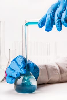 laboratorian pours reagent in the flask on a white background
