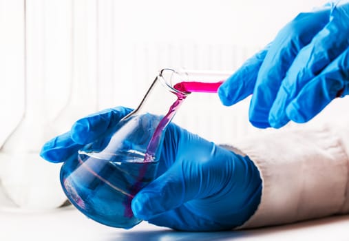 assistant reagent pouring into the flask on a white background