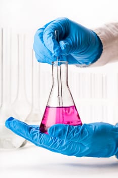 laboratorian mix reagents in the flask on a white background