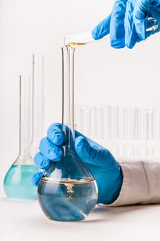 assistant pours reagent in the flask on a white background