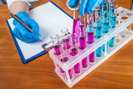 assistant of describes the result from the test tubes on a wooden background