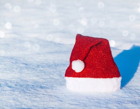 Christmas cap with bubo lying on a snowy background