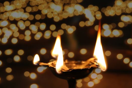 A holy ritual lamp lit in temple on the occasion of Diwali festival in India, on the backdrop of other blurred lamps behind.