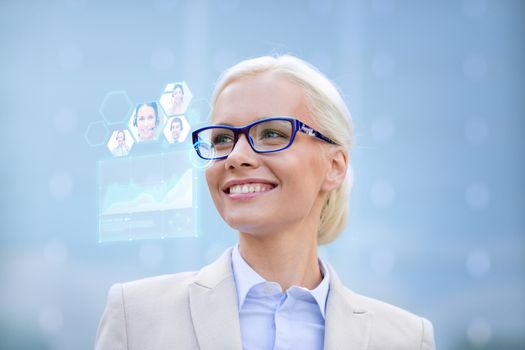 business, people, future technology and communication concept - young smiling businesswoman in eyeglasses with virtual screen, video chat and charts projection outdoors