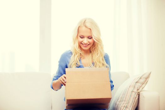 transportation, post and people concept - smiling young woman opening cardboard box at home