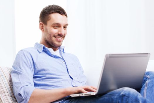 technology, home, people and lifestyle concept - smiling man working with laptop at home