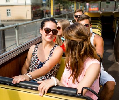 friendship, travel, vacation, summer and people concept - group of smiling friends traveling by tour bus