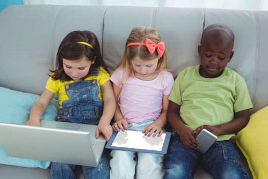 Happy kids sitting together with a tablet on the couch