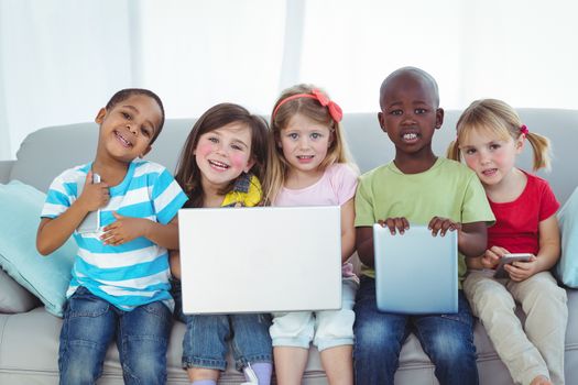 Happy kids using technology while sitting on the couch