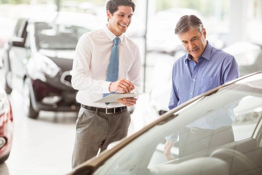 A man showing a car to the salesman at new car showroom