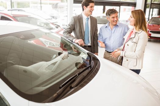 Smiling businessman presenting a car at new car showroom