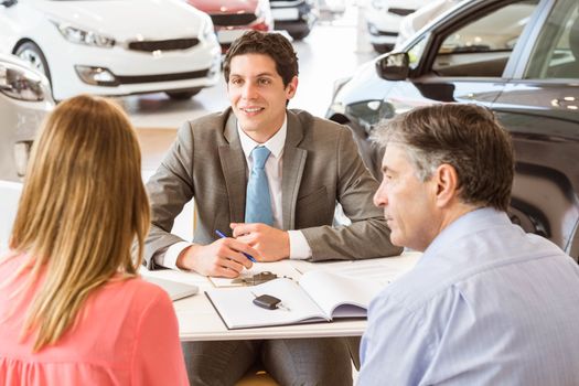 Smiling couple buying a new car at new car showroom