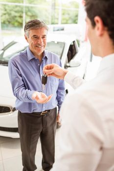 Businessman giving car key to a customer at new car showroom