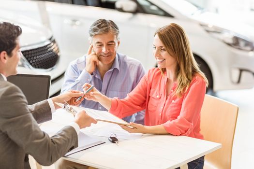 Smiling couple buying a new car at new car showroom