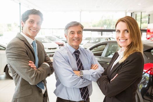 Group of smiling business team standing together at new car showroom