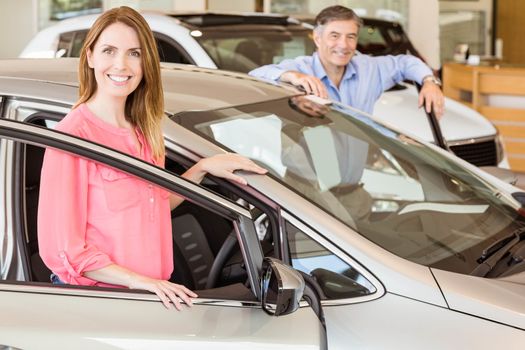 Smiling couple leaning on car at news car showroom