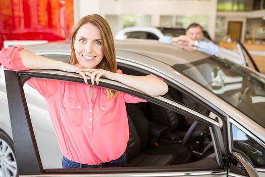 Smiling couple leaning on car at news car showroom