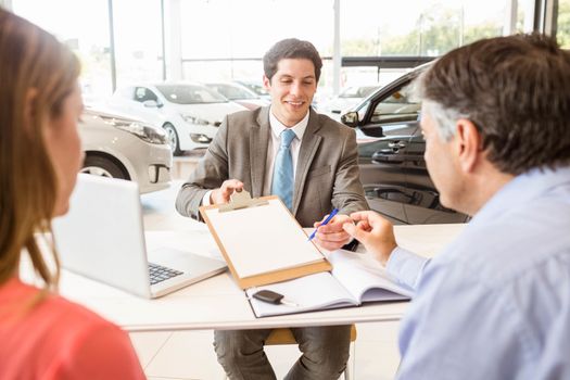 Smiling couple buying a new car at new car showroom