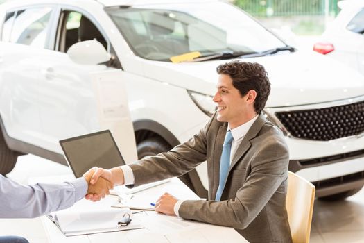 Smiling couple buying a new car at new car showroom