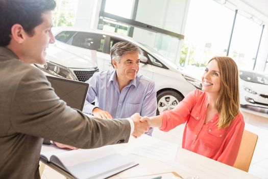 Smiling couple buying a new car at new car showroom