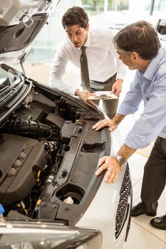 Businessman explaining the car details at new car showroom