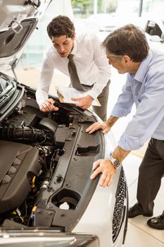 Businessman explaining the car details at new car showroom