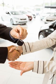 Salesman offering car key to a customers at new car showroom