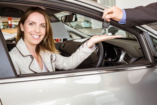 Salesman offering car key to a customers at new car showroom