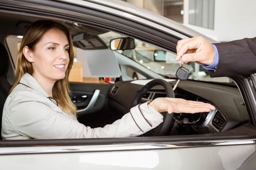 Salesman offering car key to a customers at new car showroom