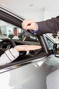 Salesman offering car key to a customers at new car showroom