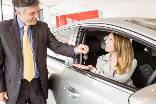 Salesman offering car key to a customers at new car showroom