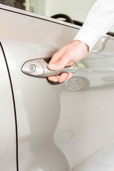  Man holding a car door handles at new car showroom