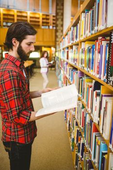 Hipster student picking a book in library at the university