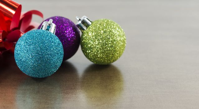 blue,pink and green christmas balls on brown gold background