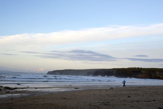 woman walking at rocky beach near ballybunion on the wild atlantic way ireland on a cold day