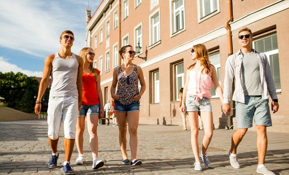 friendship, travel, tourism, summer vacation and people concept - group of smiling teenagers walking in the city