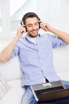 technology, home, music and lifestyle concept - smiling man with laptop and headphones at home