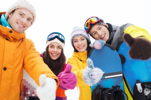 winter, leisure, extreme sport, friendship and people concept - happy friends with snowboards showing thumbs up