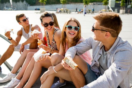 friendship, leisure, summer and people concept - group of smiling friends in sunglasses sitting with food on city square