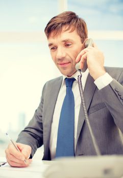 technology, business, communication and office concept - handsome businessman working with phone and documents