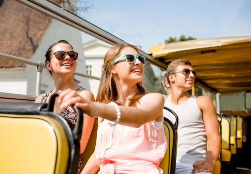 friendship, travel, vacation, summer and people concept - group of smiling friends traveling by tour bus